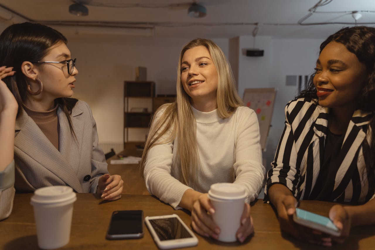 trusted-partner Three young women having a lively conversation over coffee in an office setting.